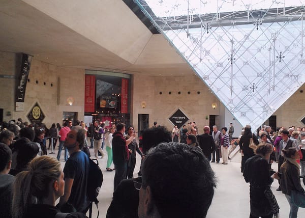 En stor folksamling och turister under den omvända glaspyramiden i Carrousel du Louvre i Paris, som visar urban trängsel